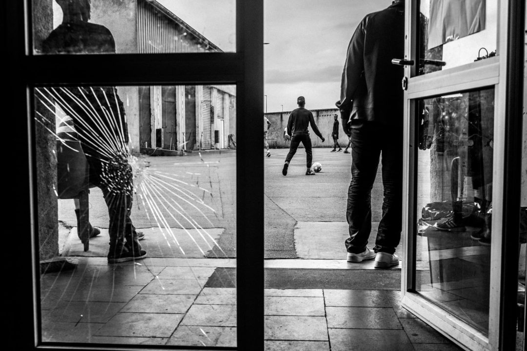 France, Bayonne, 2019-06-01. Pausa is the reception centre for refugee migrant and asymul seekers after they have crossed the border between France and Spain. They rest here for a few days before setting off again.
Here, a football match in the centre s outdoor courtyard.
Pausa est le centre d accueil des migrants refugies et demandeurs d asile apres qu ils aient passe la frontiere entre la France et l Espagne. Il s y reposent quelques jours avant de reprendre leur route. 
Ici, un match de football dans la cour exterieure du centre. Photographie par Guillaume FAUVEAU / HANS LUCAS.